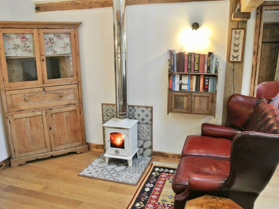 A living room with a stove and bookshelf at Nest Holiday Hideaway Wren Cottage Stunning Area, Picklescott near Church Stretton
