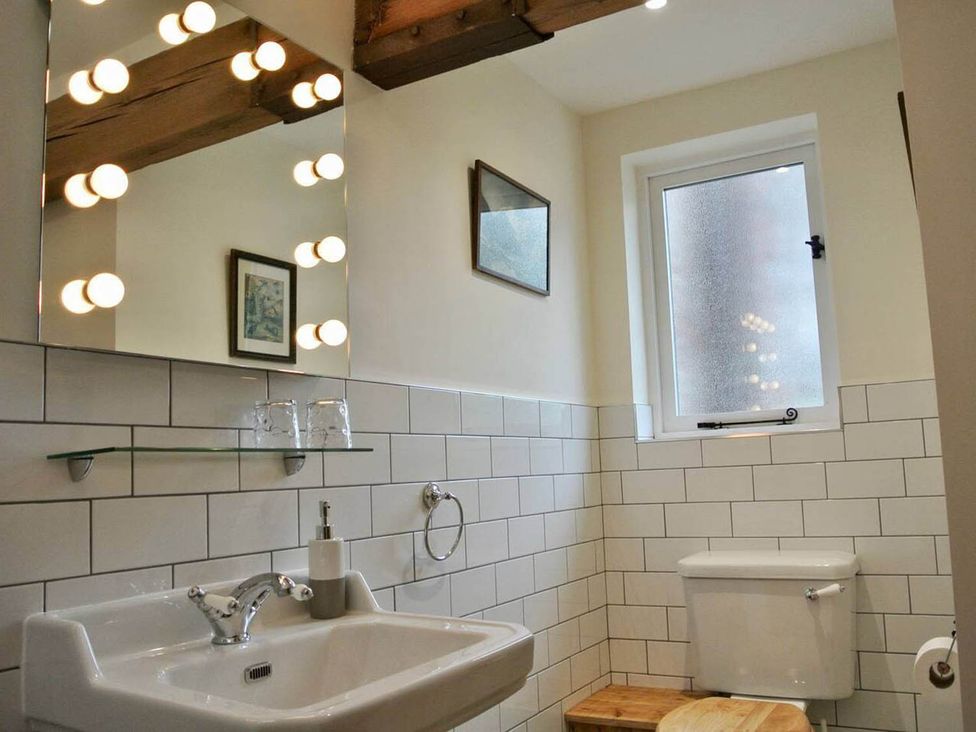 A bathroom featuring a sink, mirror, toilet, and window at Nest Holiday Hideaway Wren Cottage Stunning Area, Picklescott near Church Stretton