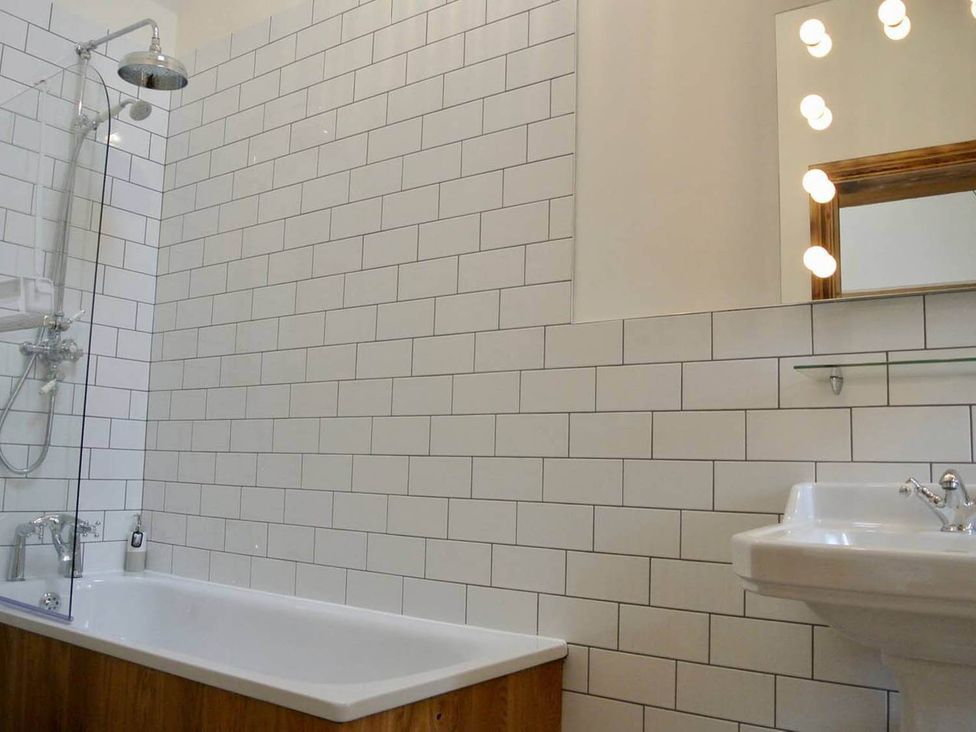 A bathroom with a bathtub, shower, sink and mirror at Nest Holiday Hideaway Wren Cottage Stunning Area Picklescott near Church Stretton