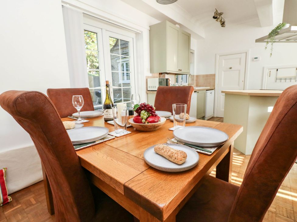 A dining table set with plates and fruit at Osmington Cottage Annex