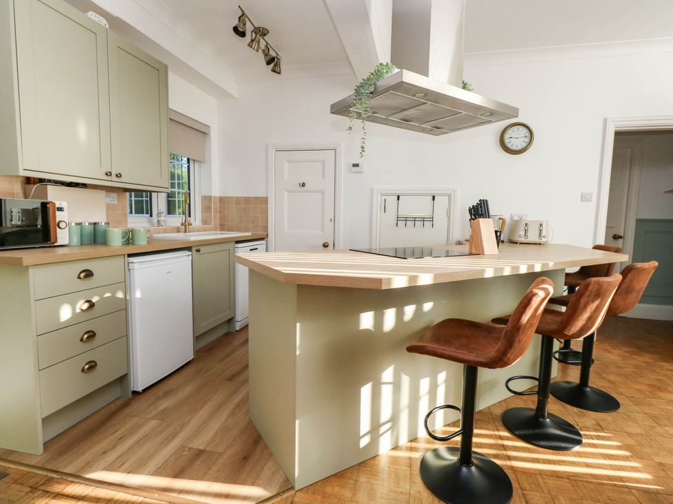 A kitchen with a kitchen island and bar stools at Osmington Cottage Annex 