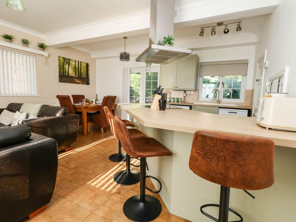 A kitchen featuring bar stools, a sink, and a dining table at Osmington Cottage Annex