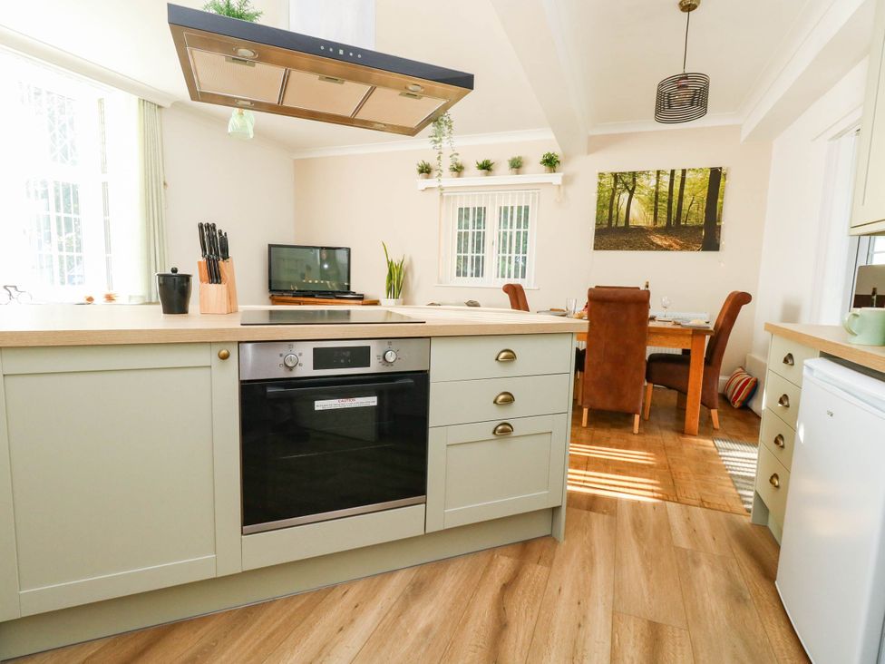 A kitchen with a stove and dining area at Osmington Cottage Annex 