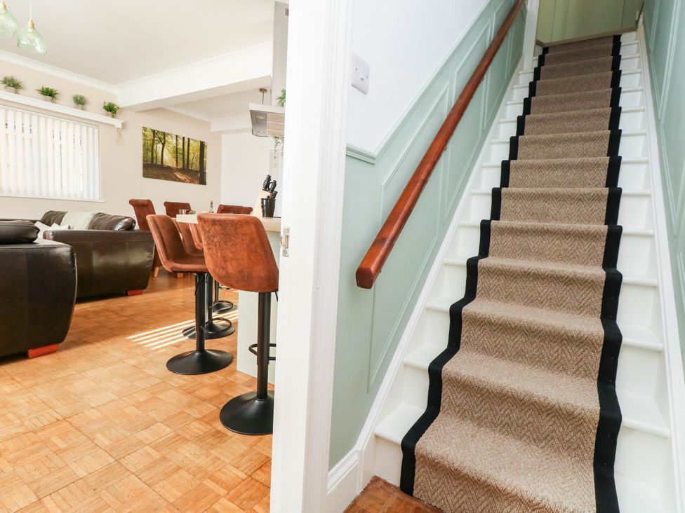 A living room with stairs and bar stools at Osmington Cottage Annex
