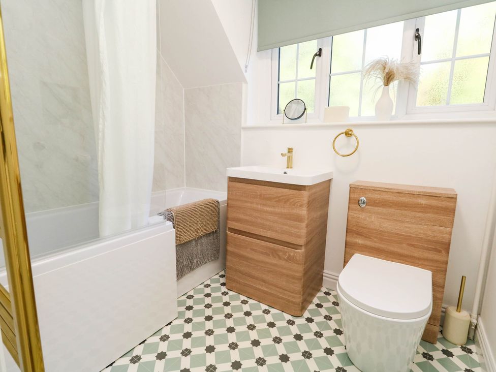 A bathroom with a bathtub, vanity unit, toilet, and window at Osmington Cottage Annex