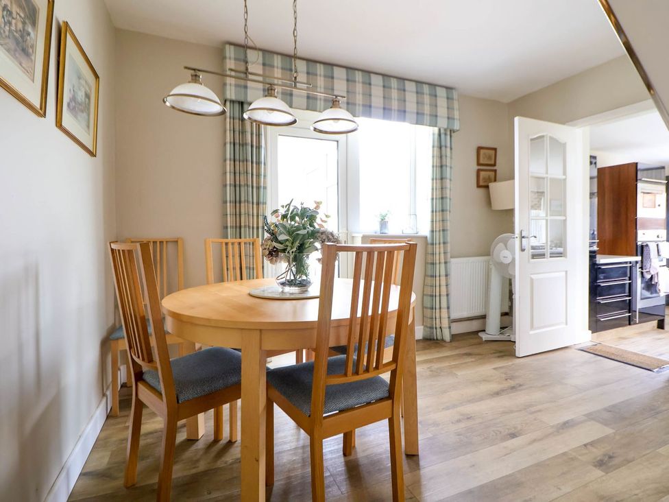 A dining room with a wooden table and chairs at Branwen in Talacre