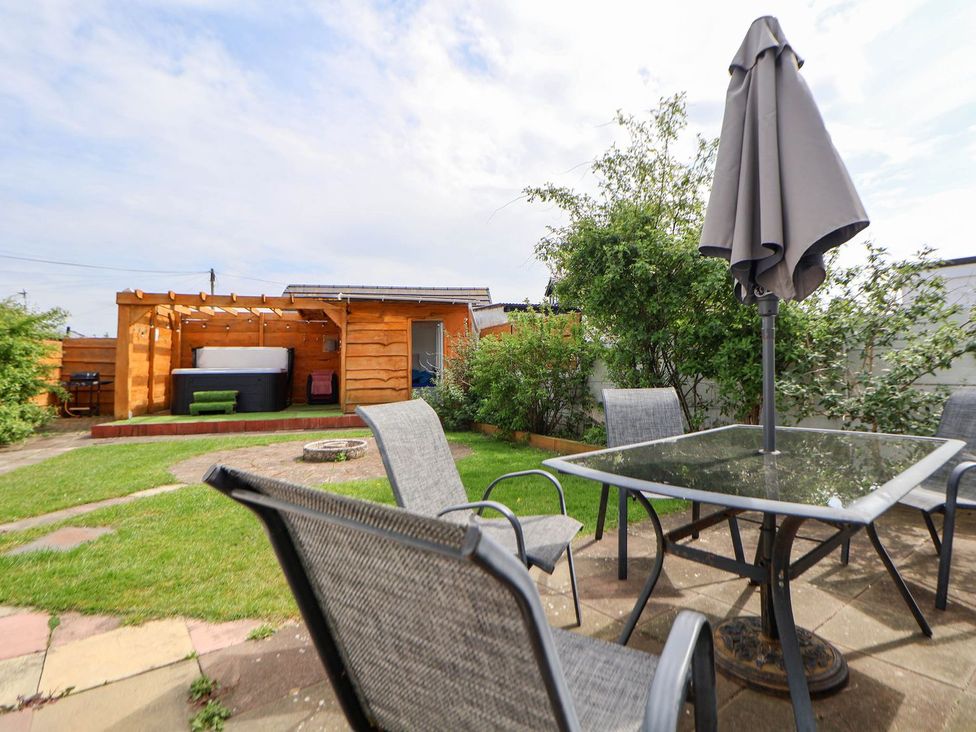 A garden with a table and chairs and a hot tub at Branwen in Talacre