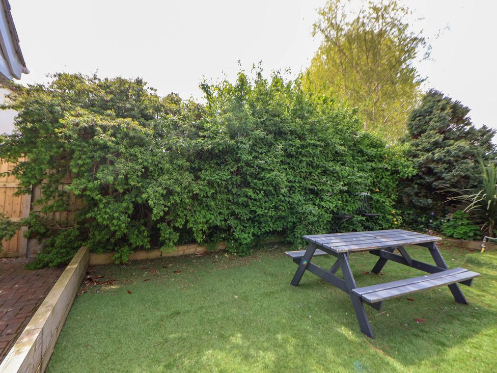 A garden with a picnic table and benches at Branwen in Talacre