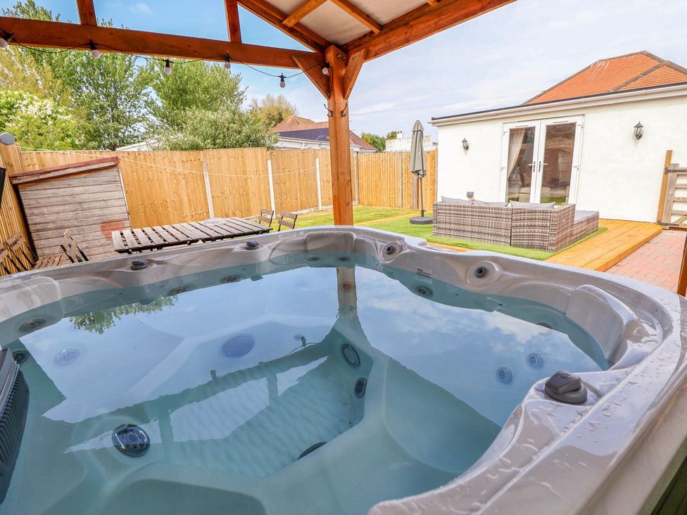 A hot tub on a patio with outdoor furniture at Brimrod in Talacre