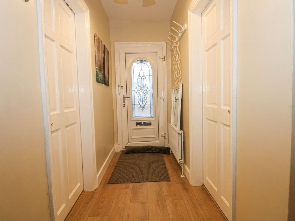 A hallway with a front door and coat rack at Brimrod in Talacre