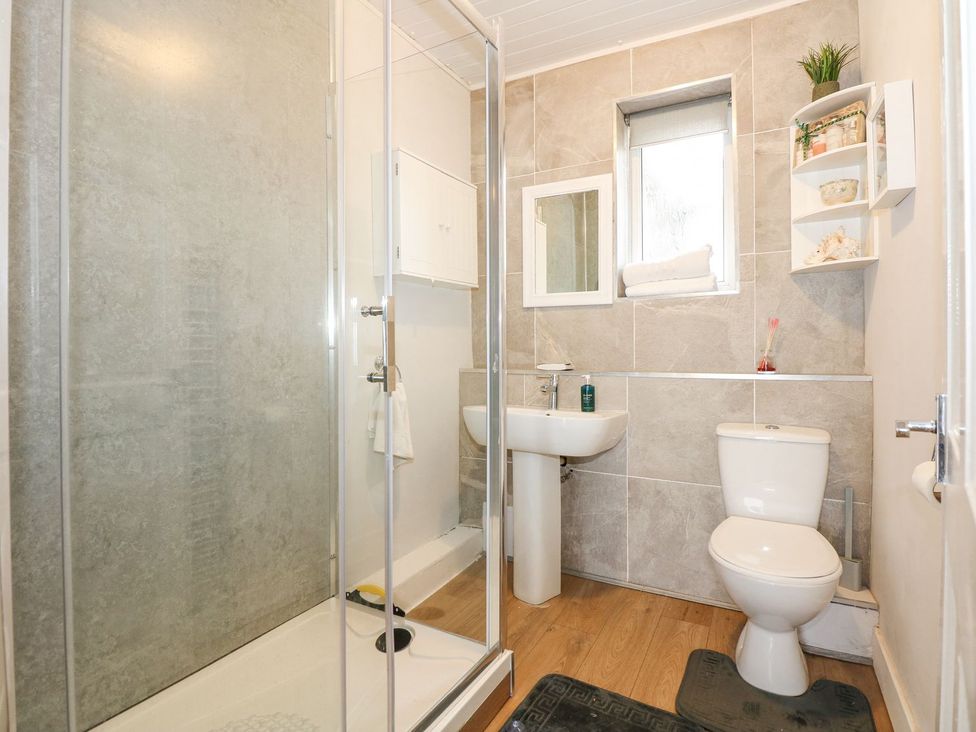 A bathroom with a shower, toilet, and sink at Brimrod in Talacre