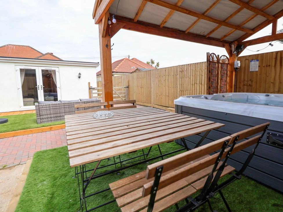 A garden with a hot tub and a dining table at Brimrod in Talacre