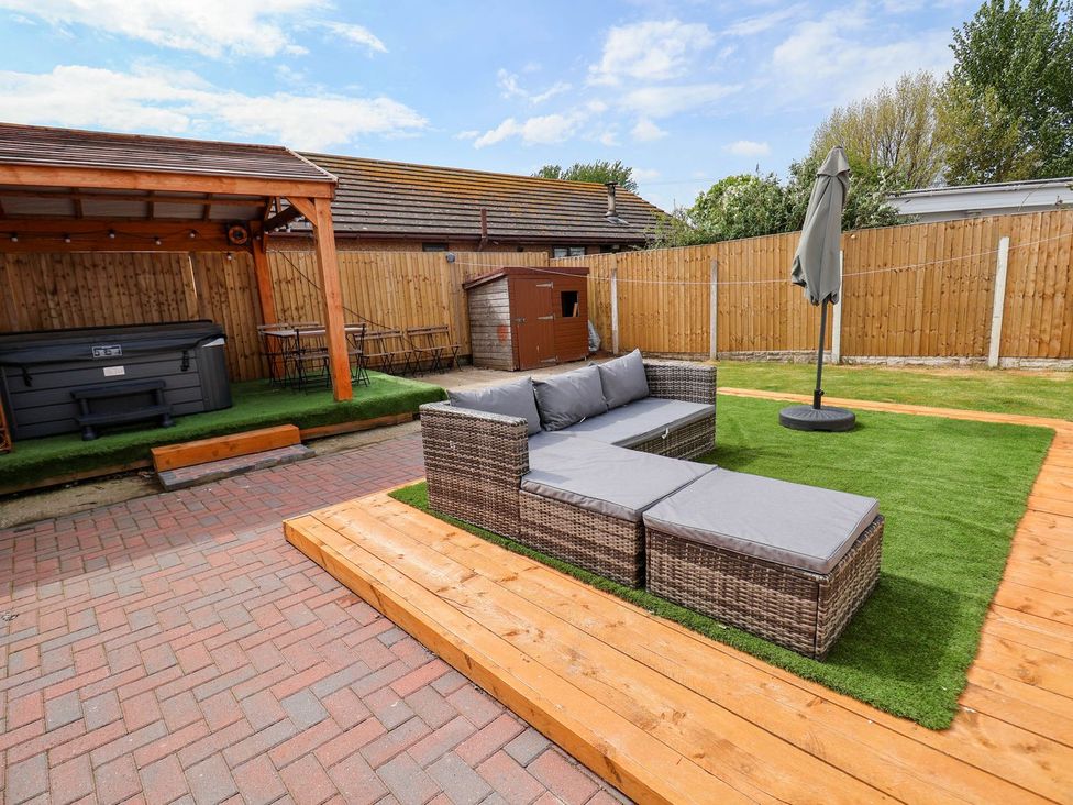 A garden with a patio sofa and an umbrella at Brimrod in Talacre