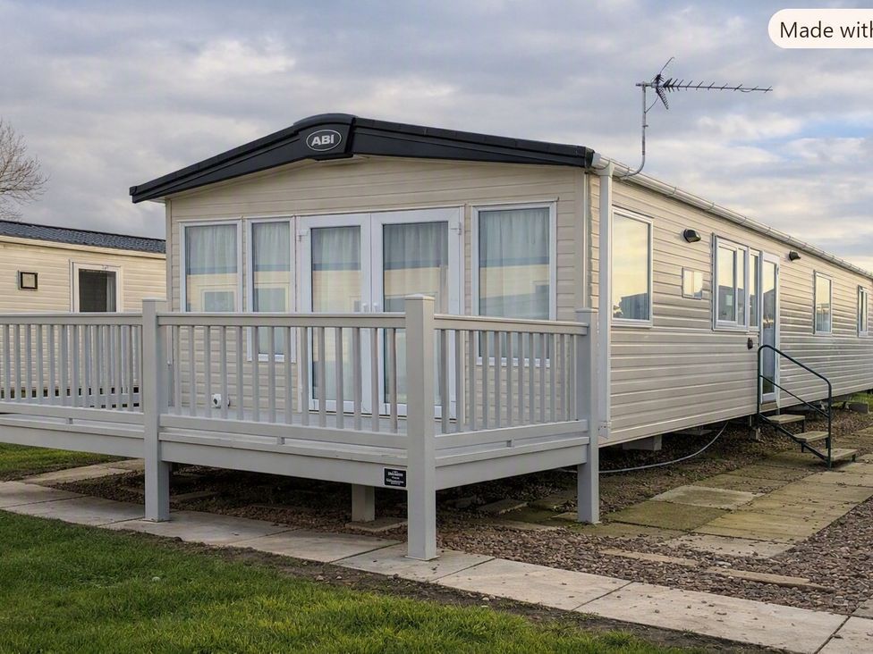 A caravan with decking and windows at Coastfields Holiday Village in Skegness