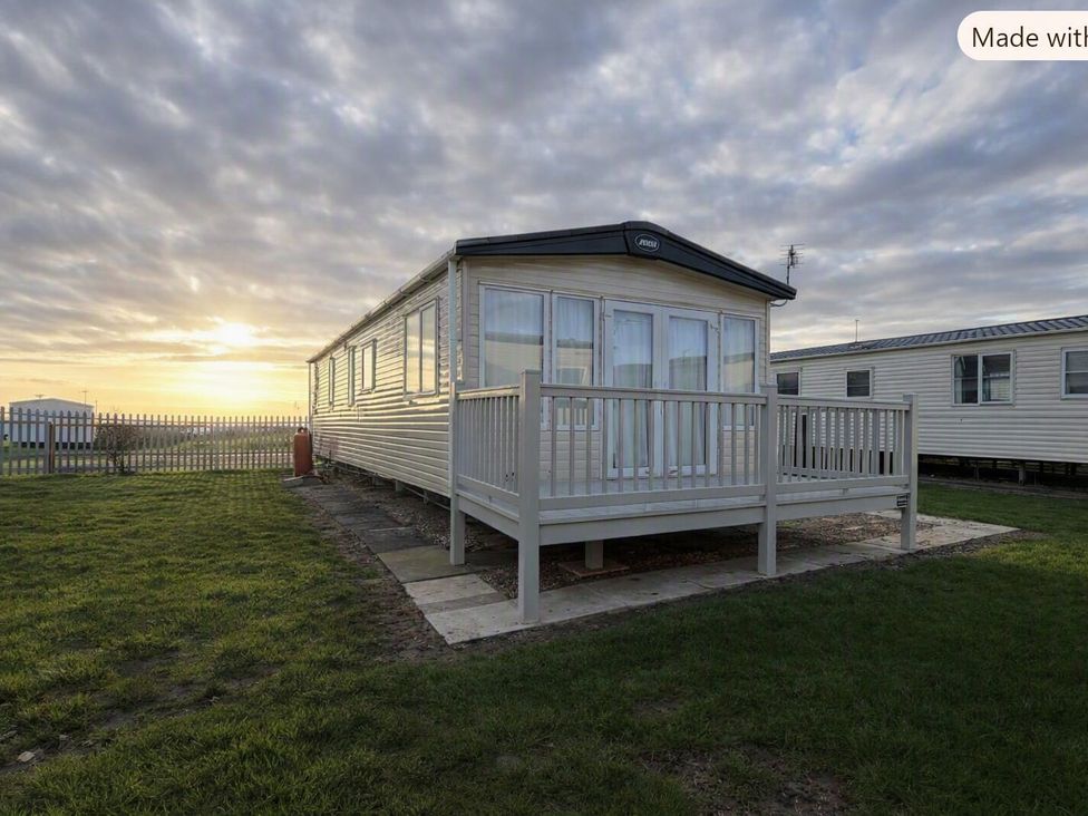 A holiday home with a balcony and fence at Coastfields Holiday Village in Skegness
