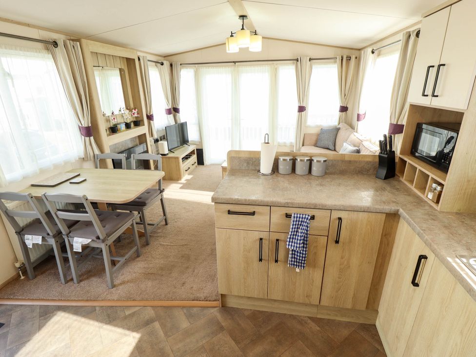 A living room with kitchen area and dining table at Coastfields Holiday Village in Ingoldmells