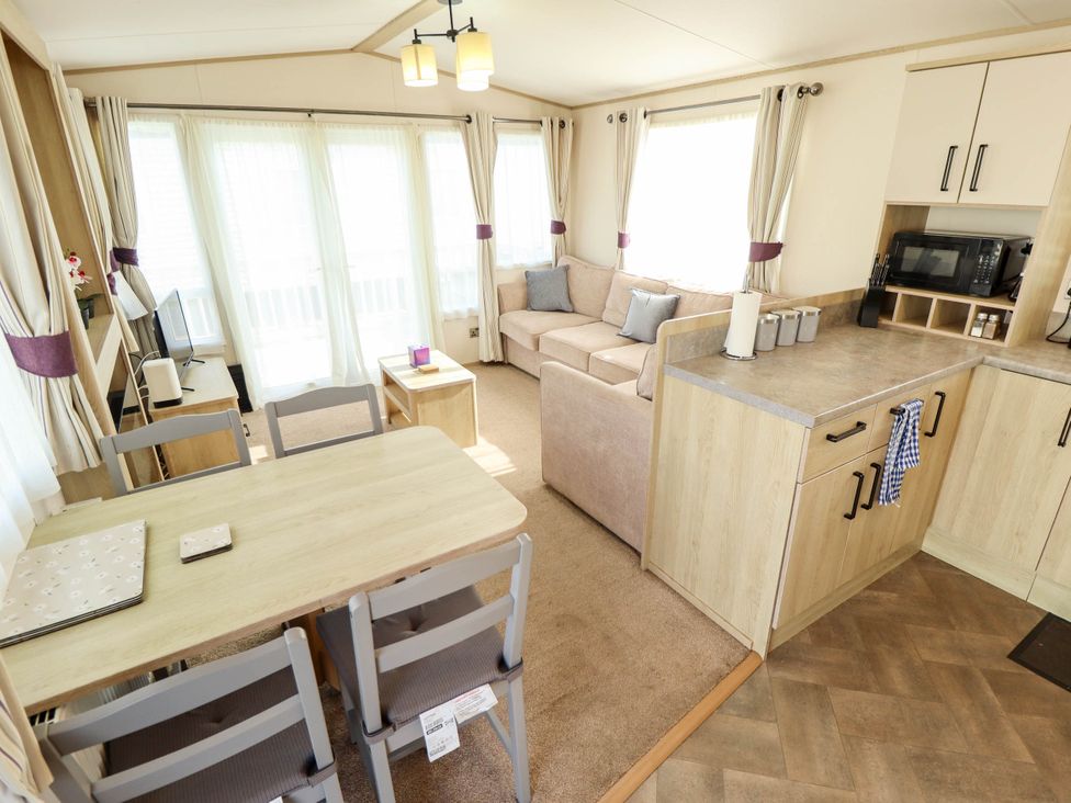 A living room and kitchen area with a sofa and dining table at Coastfields Holiday Village in Ingoldmells