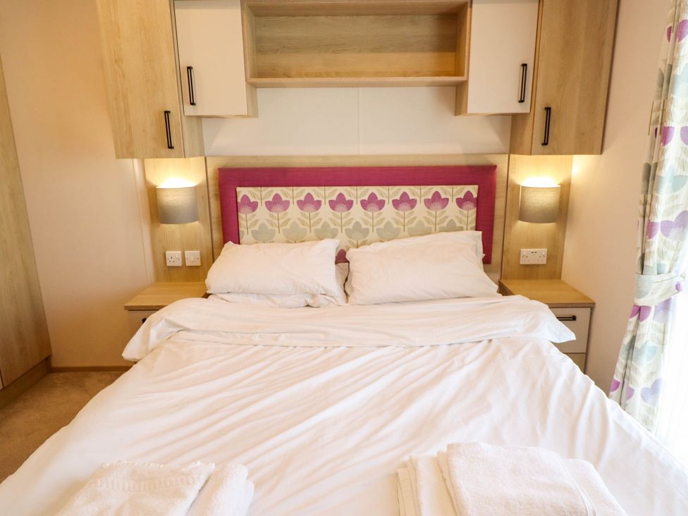 A bedroom with a bed and bedside table at Coastfields Holiday Village in Ingoldmells