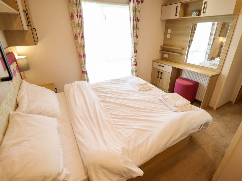 A bedroom with queen bed and a dressing table at Coastfields Holiday Village in Ingoldmells