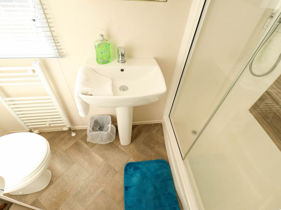 A bathroom with a sink, toilet, shower, and radiator at Coastfields Holiday Village in Ingoldmells