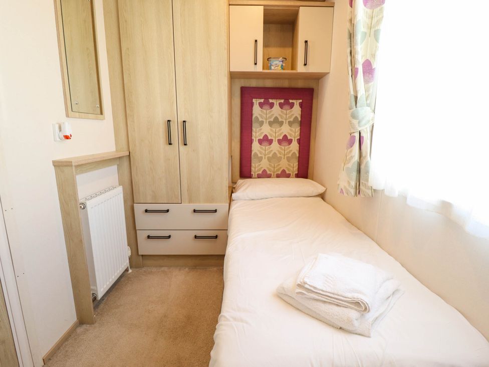 A bedroom with a single bed and wardrobe at Coastfields Holiday Village in Ingoldmells