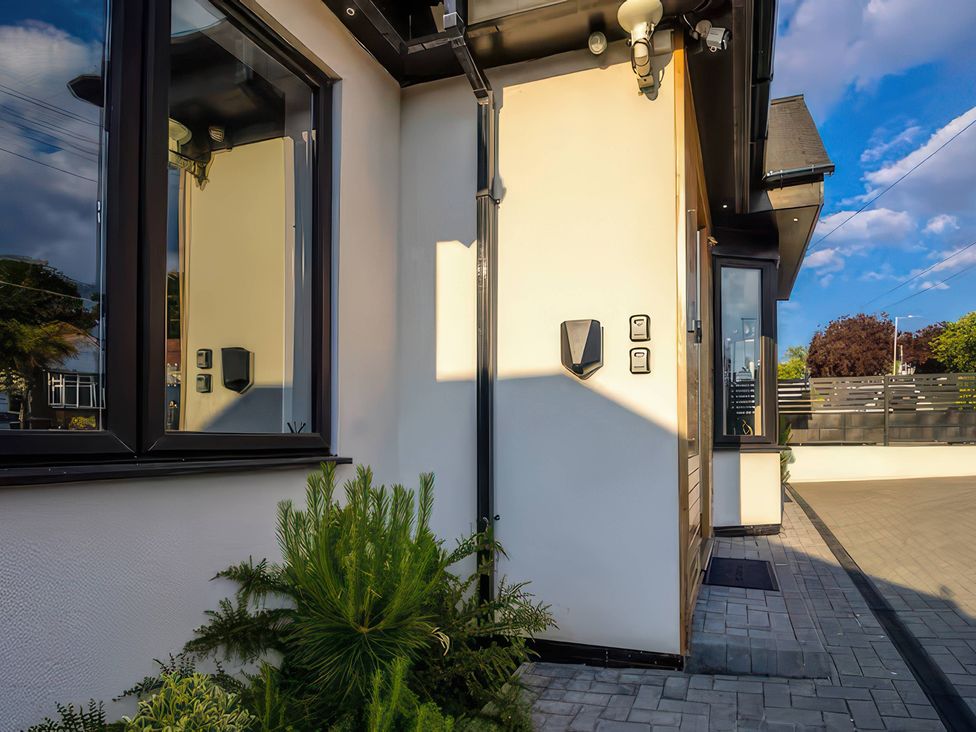 An exterior view of a house with plants and a light fixture at 19 Hillside Road in Northwood, Hertfordshire