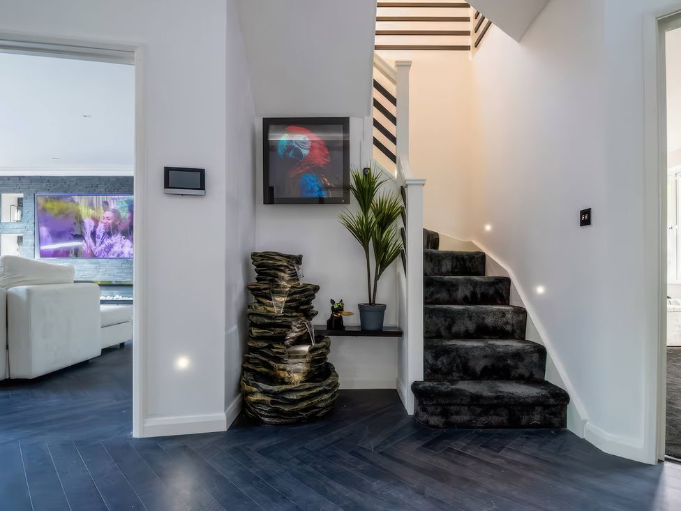 A hallway with a staircase and water feature at 19 Hillside Road, Northwood, Hertfordshire