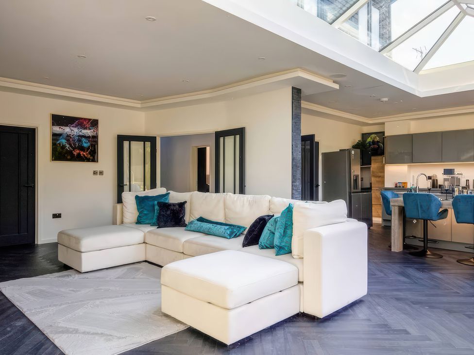 A living room with a sofa and kitchen area at 19 Hillside Road Northwood, Hertfordshire