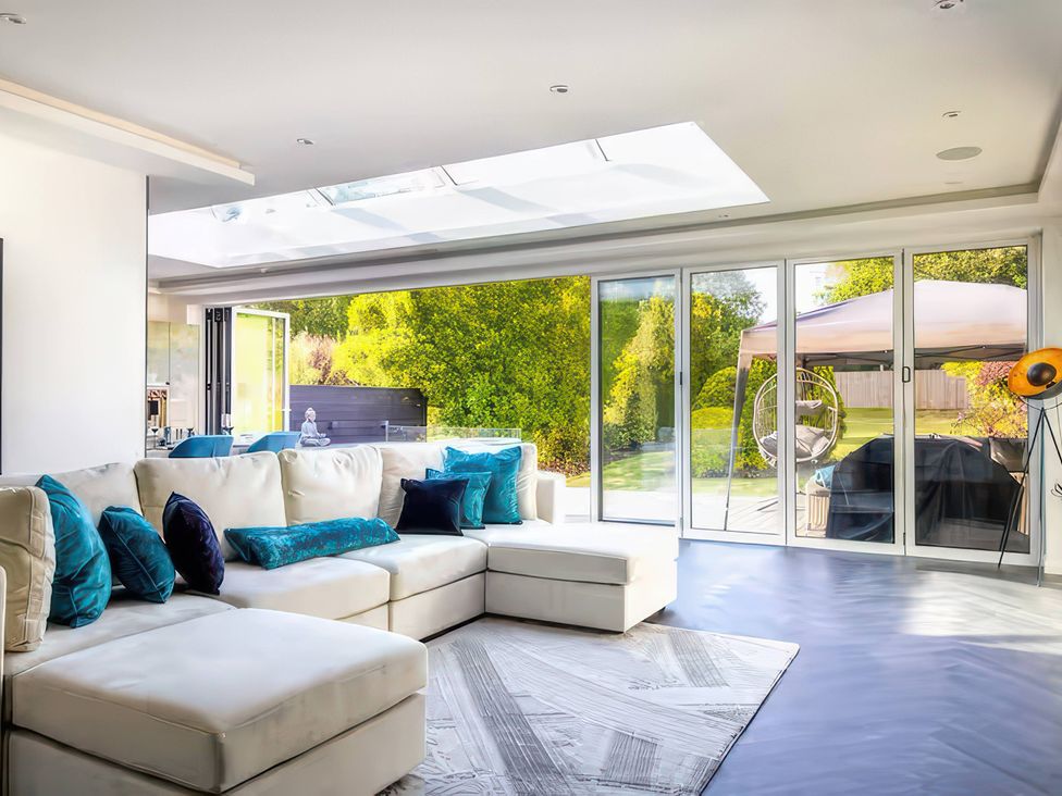 A living room with a sofa and sliding glass doors at 19 Hillside Road, Northwood, Hertfordshire
