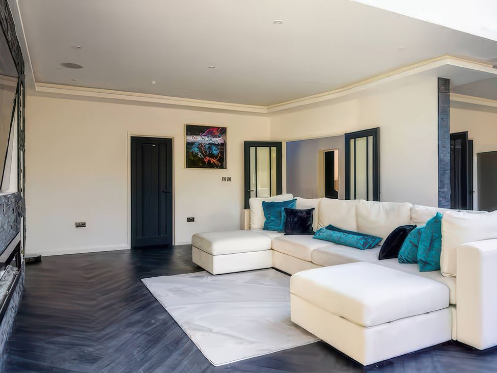 A living room with a large sofa and artwork at 19 Hillside Road in Northwood, Hertfordshire