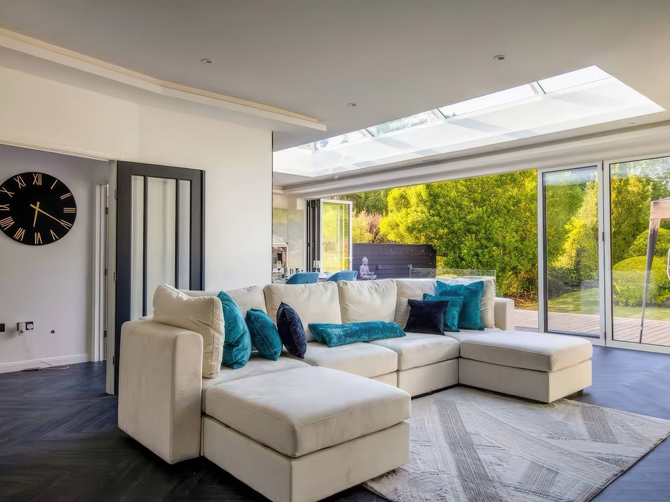 A living room with a sofa and glass doors at 19 Hillside Road in Northwood, Hertfordshire
