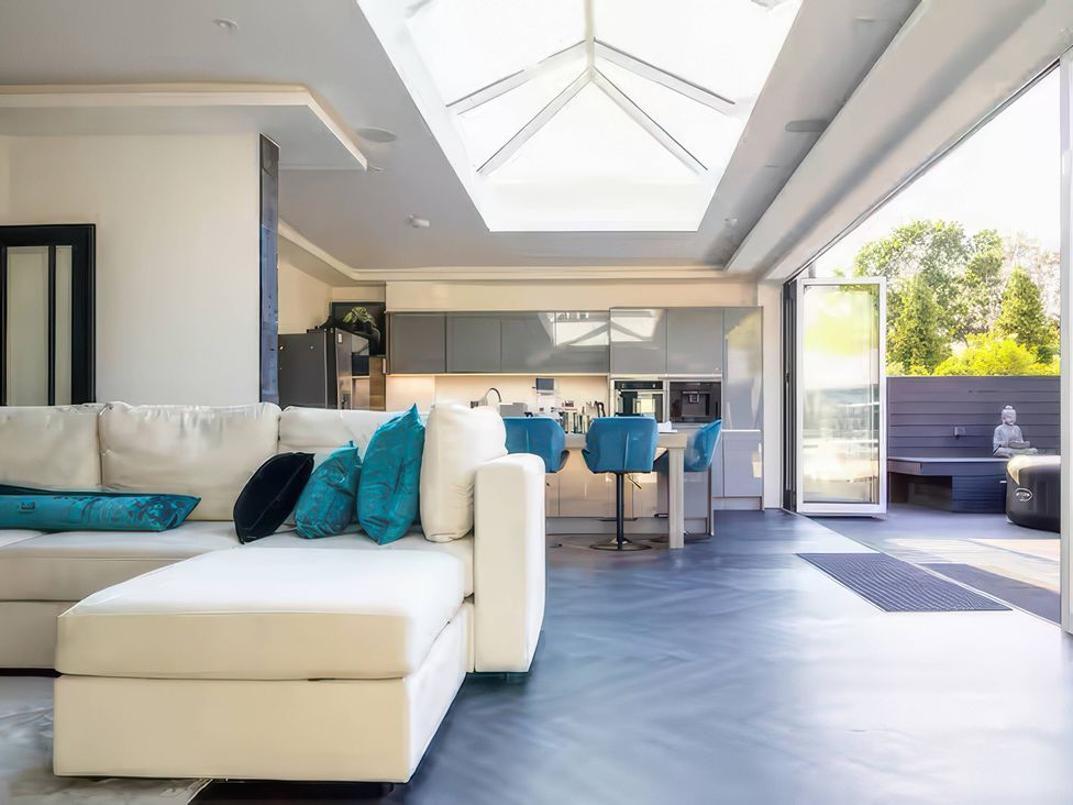 A living room with a sofa and kitchen area at 19 Hillside Road in Northwood, Hertfordshire