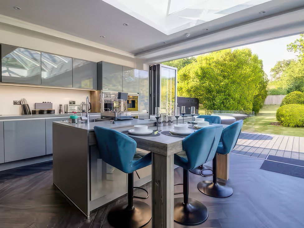 A kitchen with a table and bar stools at 19 Hillside Road Northwood, Hertfordshire