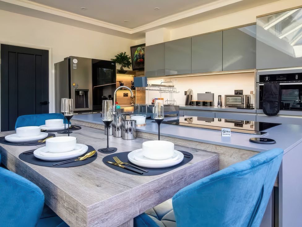 A kitchen with a dining table and modern appliances at 19 Hillside Road Northwood, Hertfordshire