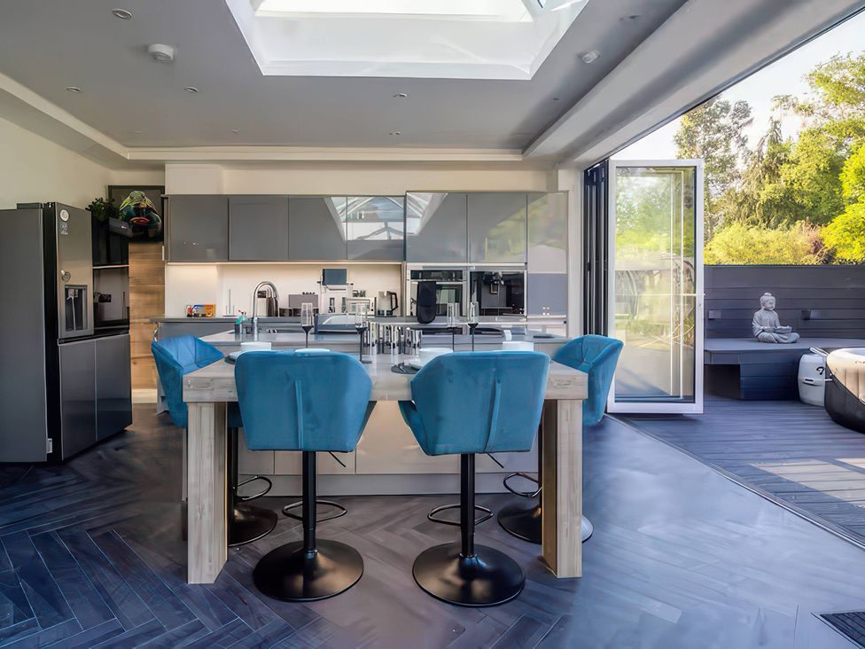 A kitchen with a skylight and bar stools at 19 Hillside Road, Northwood, Hertfordshire