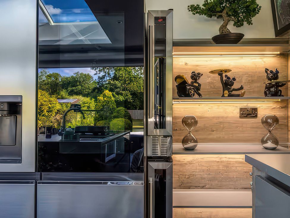 A kitchen with a refrigerator and decorative shelf at 19 Hillside Road Northwood, Hertfordshire
