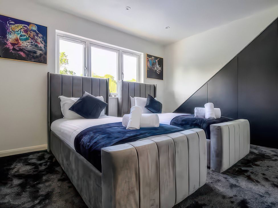 A bedroom with two beds and wall art at 19 Hillside Road Northwood, Hertfordshire