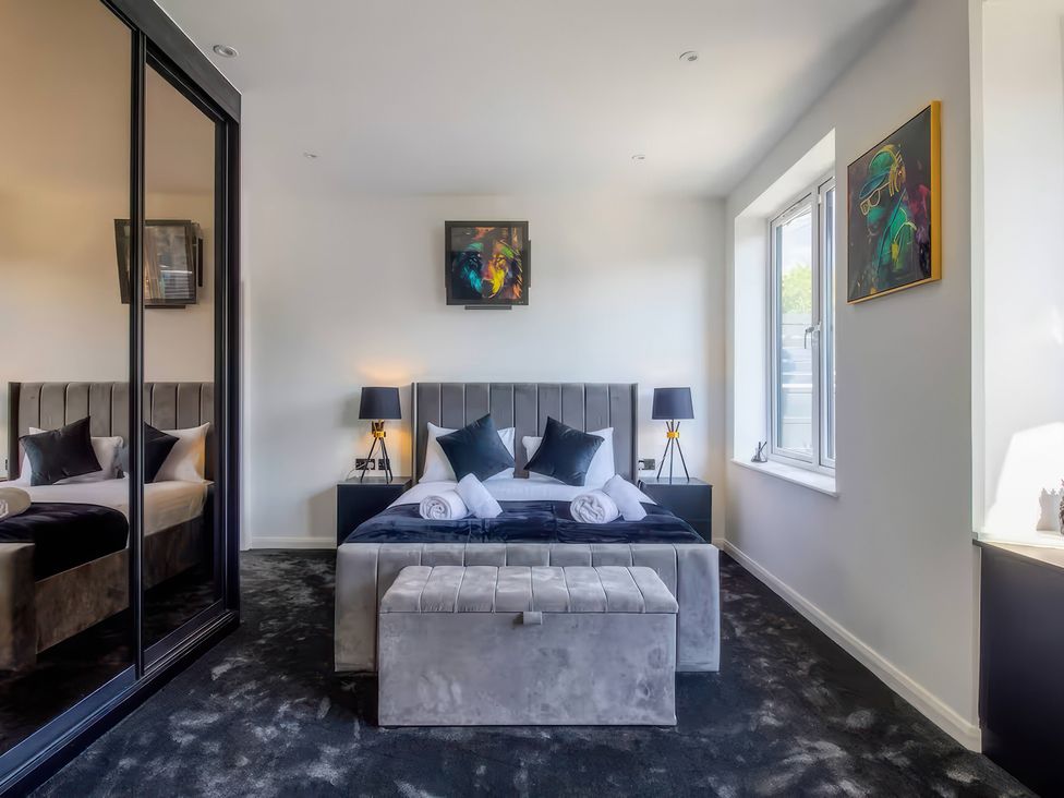 A bedroom with a bed and nightstand at 19 Hillside Road, Northwood, Hertfordshire