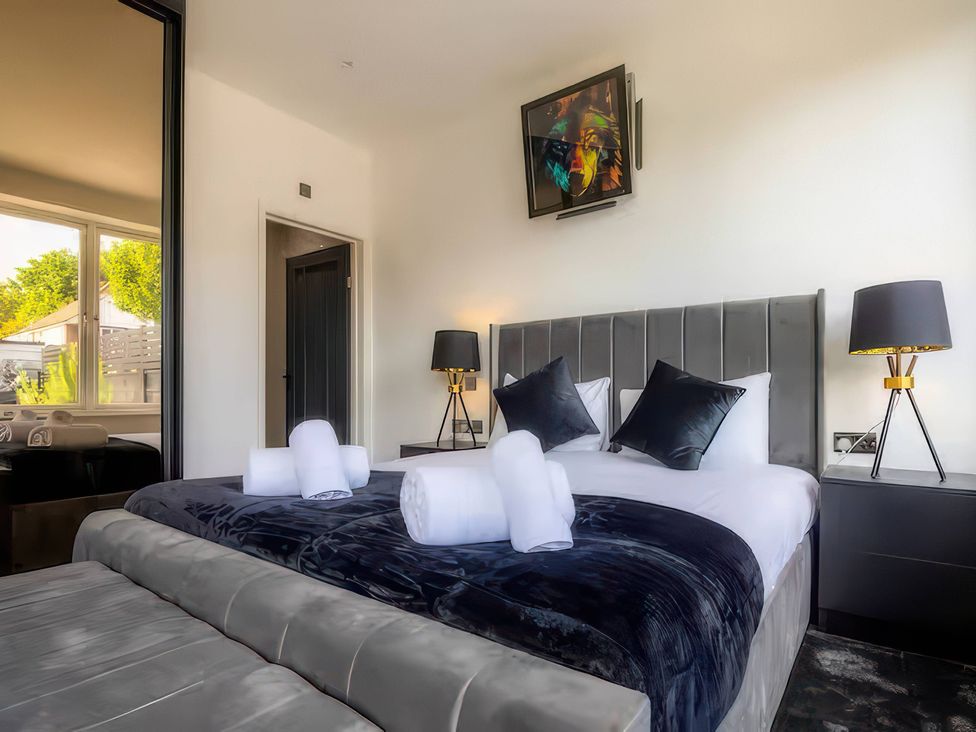 A bedroom with a bed and lamps at 19 Hillside Road, Northwood, Hertfordshire