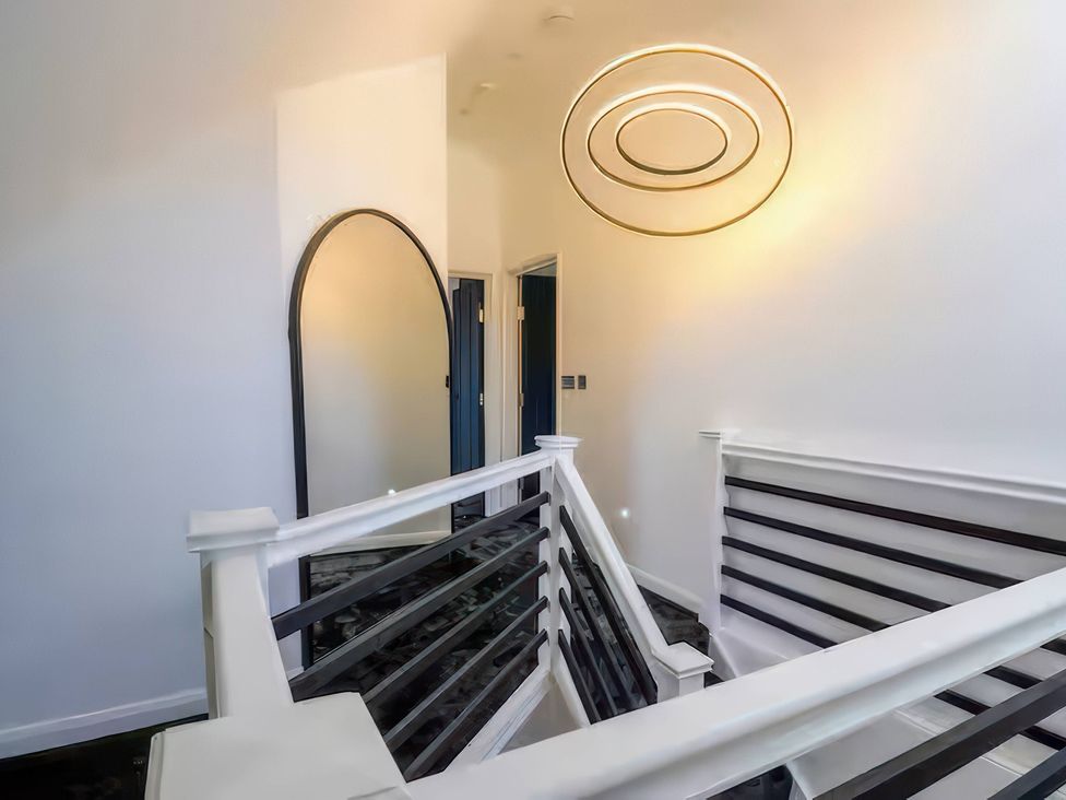 A staircase with a railing and a mirror at 19 Hillside Road in Northwood, Hertfordshire