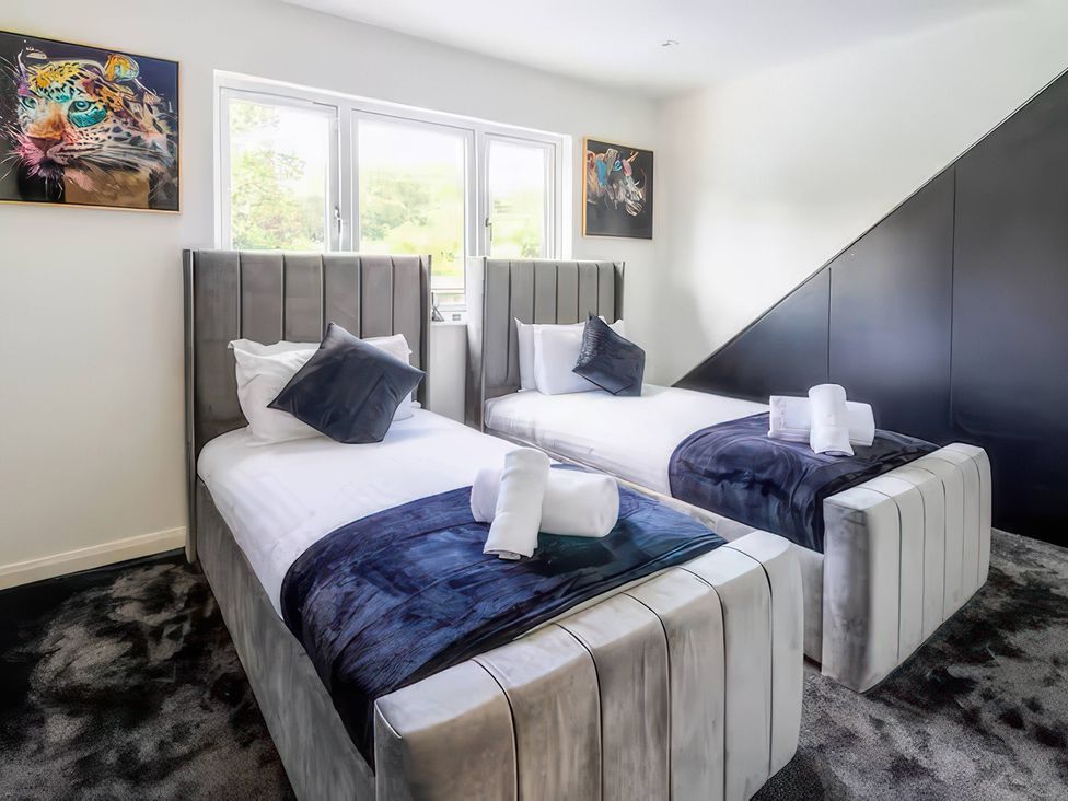 A bedroom with two beds and artwork on the wall at 19 Hillside Road Northwood, Hertfordshire