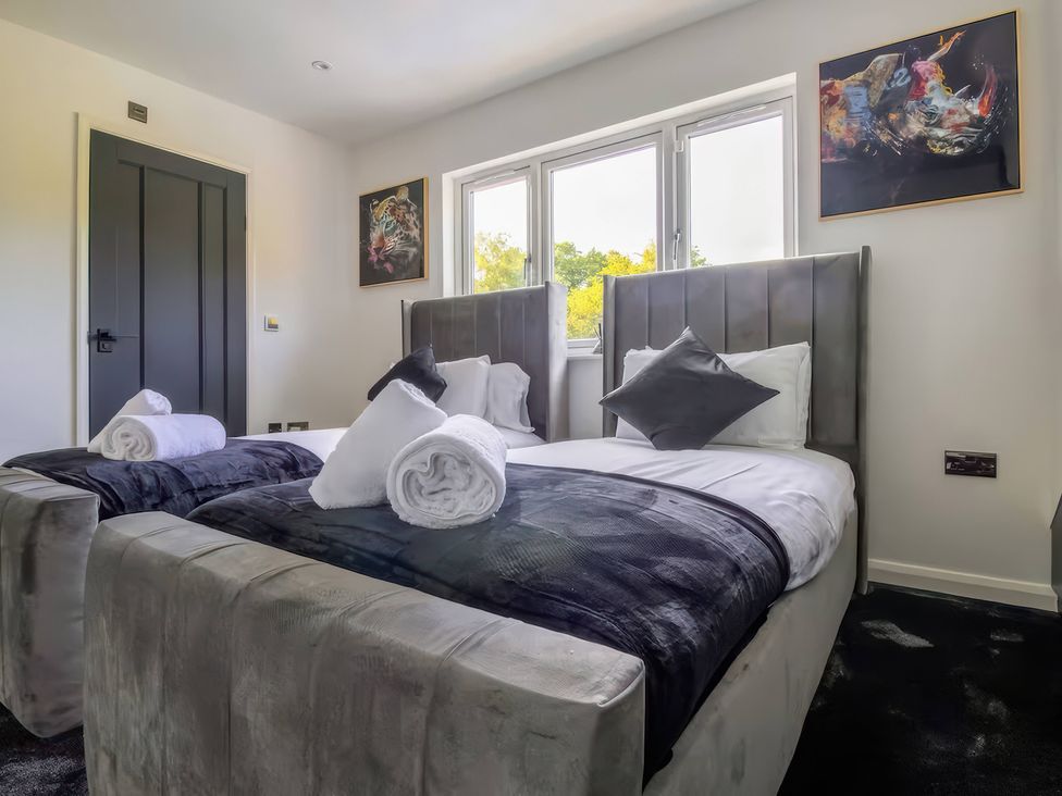 A bedroom with two beds and a door at 19 Hillside Road, Northwood, Hertfordshire