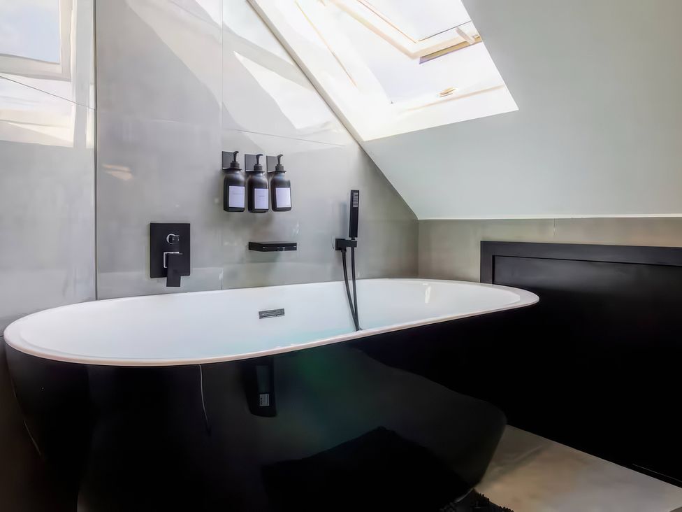 A bathroom with a bathtub and skylight at 19 Hillside Road Northwood, Hertfordshire