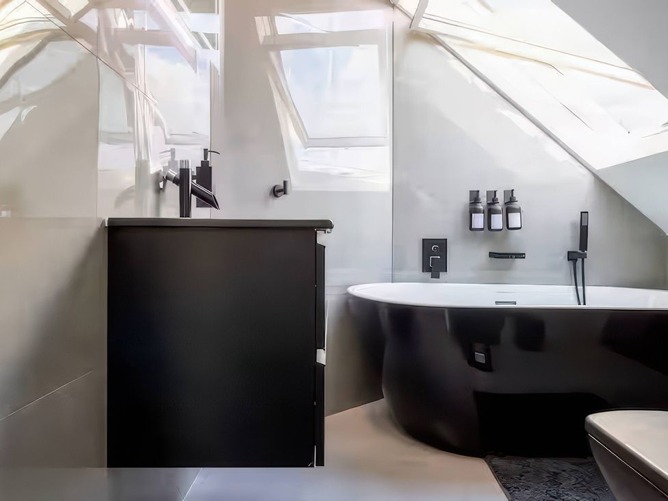 A bathroom with a black bath tub and sink at 19 Hillside Road in Northwood, Hertfordshire