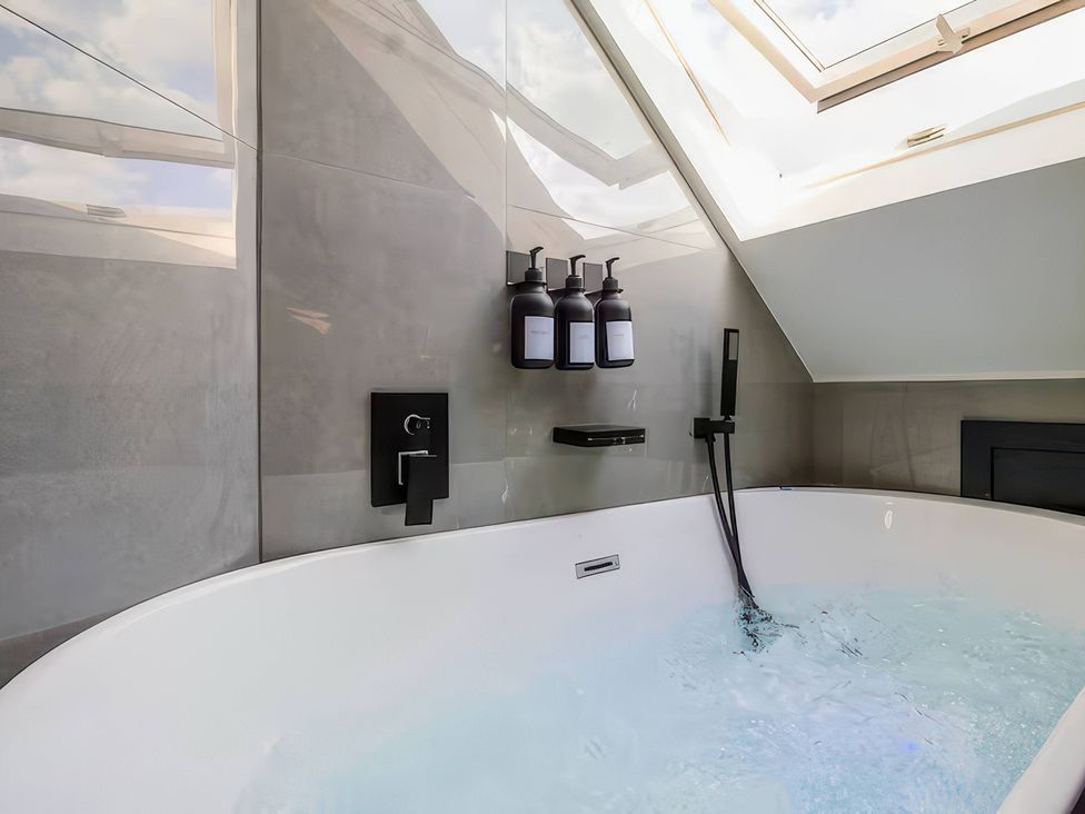 A bathroom with a bathtub and soap dispensers at 19 Hillside Road Northwood Hertfordshire