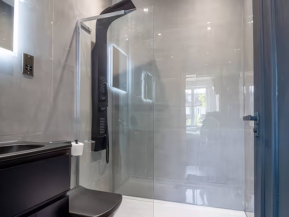 A bathroom with a shower, toilet, and sink at 19 Hillside Road in Northwood, Hertfordshire