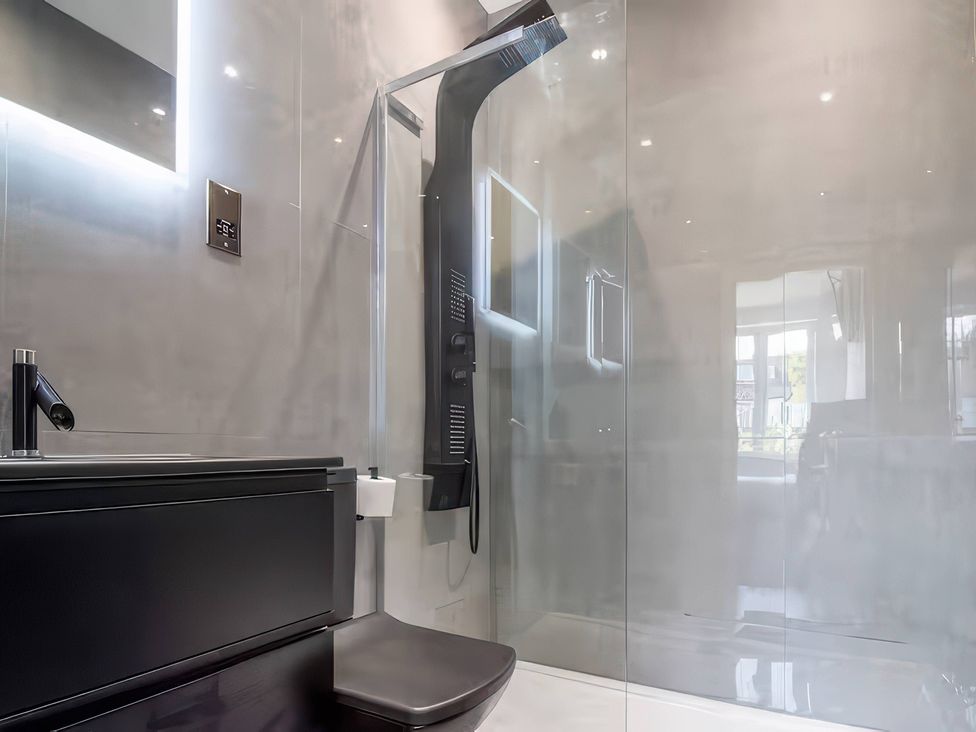 A bathroom with a shower, toilet, sink, and mirror at 19 Hillside Road in Northwood, Hertfordshire