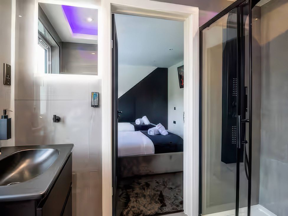 A bathroom with a sink and shower looking into a bedroom at 19 Hillside Road Northwood, Hertfordshire