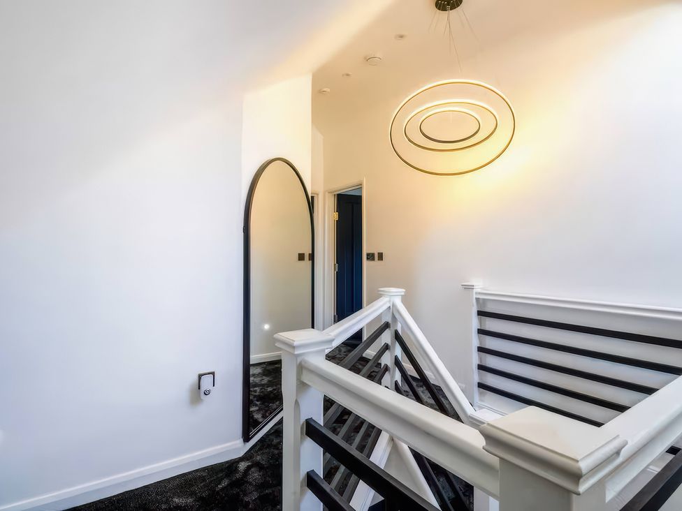 A hallway with stairs and a mirror at 19 Hillside Road in Northwood, Hertfordshire