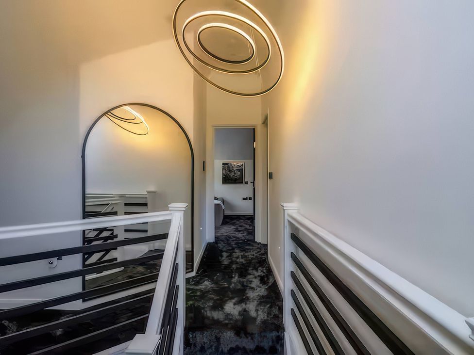A hallway with a mirror and lighting fixture at 19 Hillside Road Northwood, Hertfordshire